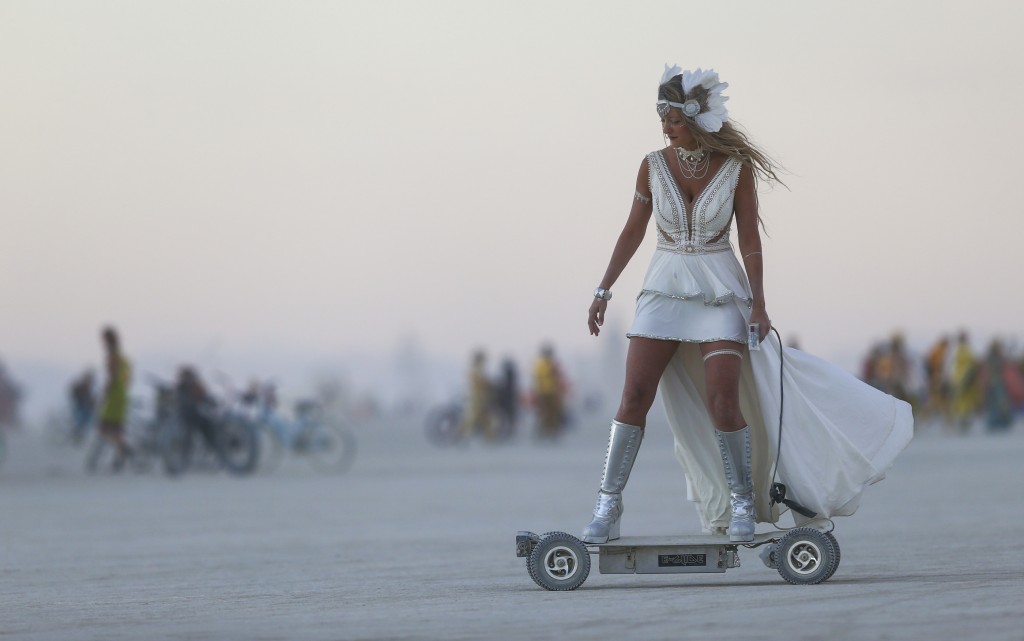 In this Wednesday, Aug. 31, 2016 photo, a woman rides an electric scooter during Burning Man at the Black Rock Desert north of Reno, Nev. (Chase Stevens/Las Vegas Review-Journal via AP)
